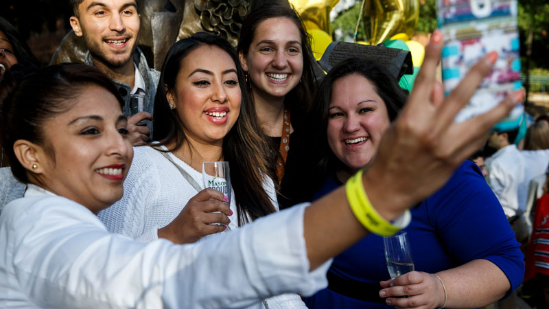 Recent Mason graduates take a group selfie during the alumni association graduate toast