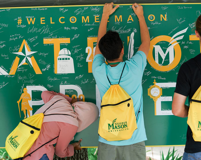 Students inscribe their signatures on their class sign during new student orientation.
