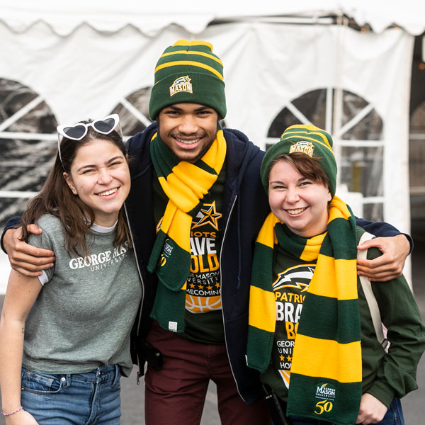 Students pose inMason scarfs and beanies during the February 2022 George Mason University Homecoming tailgate