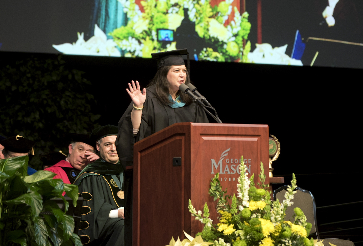 woman in cape and gown at podium