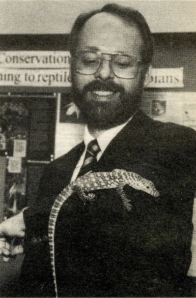 black and white photo of a man with a lizard on his arm