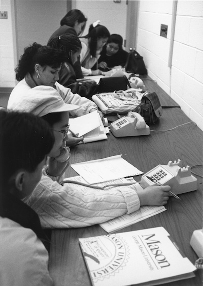 black and white photo of people at a table using touchtone phones