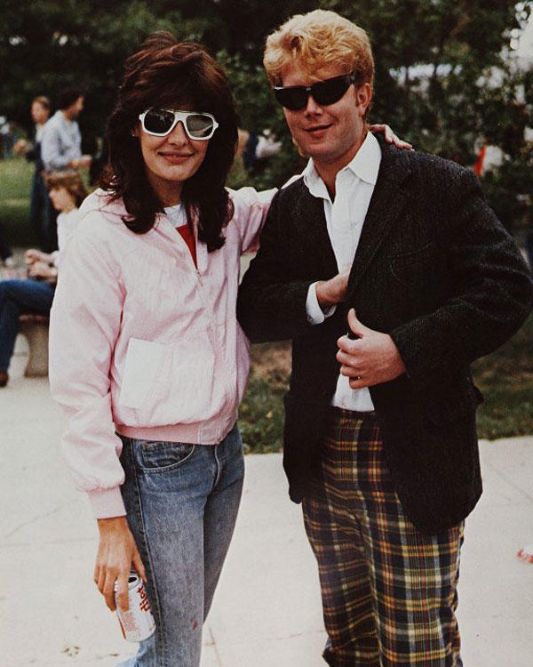 Male and female student pose for the camera. Photo from the 1984 George Mason University Yearbook. Fashions depicted: big hair, mirrored sunglasses, pastels, open collars, diet coke