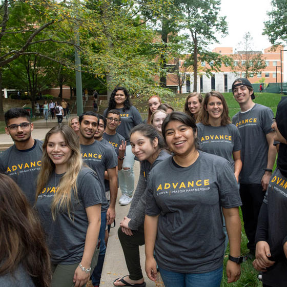 Students gathered in front of the camera wearing ADVANCE t-shirts and smiling