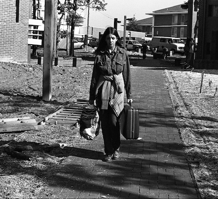 a black and white photo of girl carrying bags